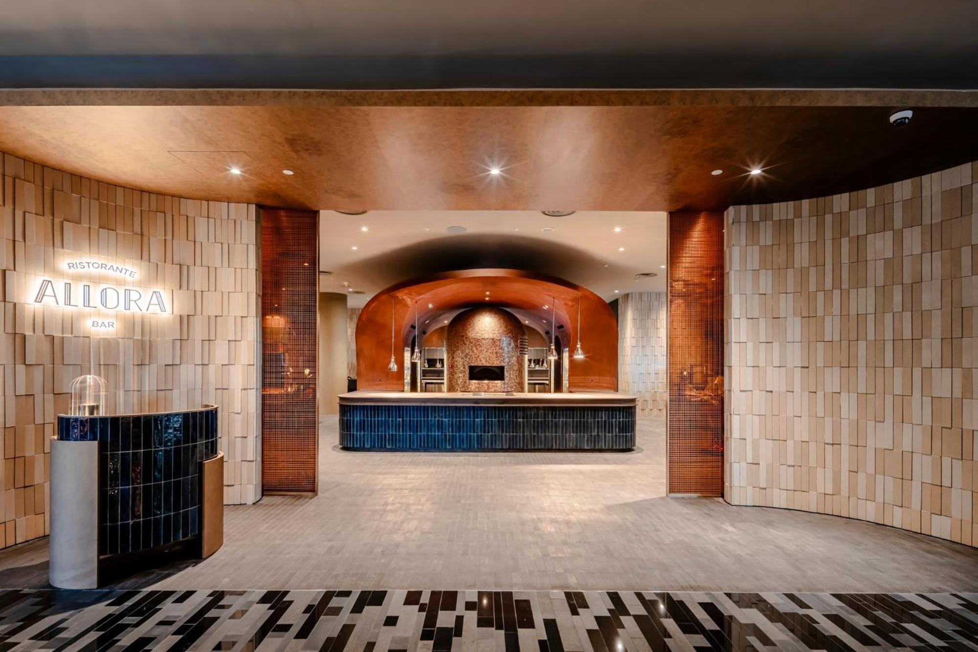 فندق كراون بلازا مطار شانجي سنغافورة المظهر الخارجي الصورة The photo shows a modern reception area, characterized by a stylish and elegant design. The space features a combination of textured wall panels, including light-colored tiles and warm-toned materials. In the center, there is a sleek reception desk a