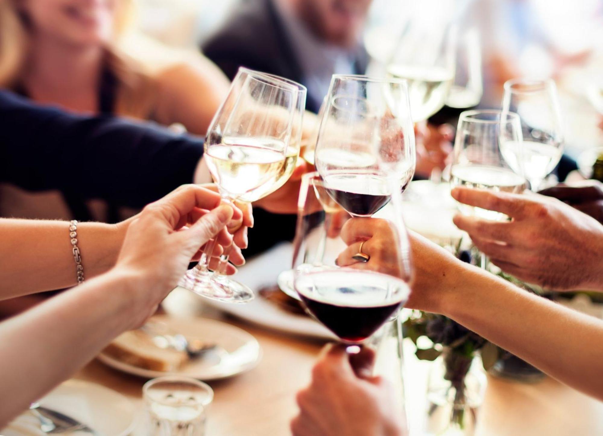 فندق كراون بلازا مطار شانجي سنغافورة المظهر الخارجي الصورة The photo shows a group of people celebrating, as indicated by the clinking of wine glasses. Several hands are holding various types of glasses filled with different beverages, including red wine and white wine. In the background, other people are ga